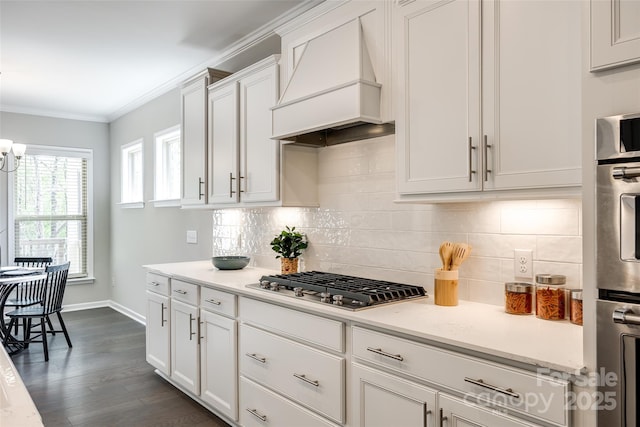 kitchen featuring crown molding, stainless steel gas cooktop, white cabinetry, tasteful backsplash, and custom range hood