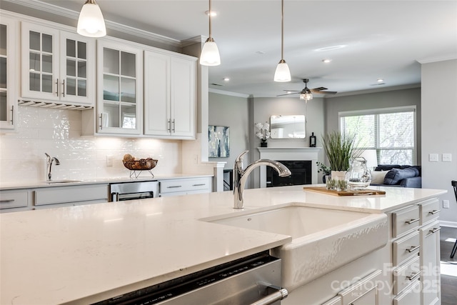 kitchen featuring decorative backsplash, ornamental molding, a sink, and open floor plan