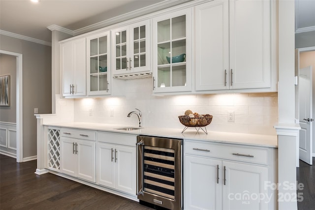 bar featuring dark wood-style flooring, ornamental molding, wine cooler, backsplash, and a sink