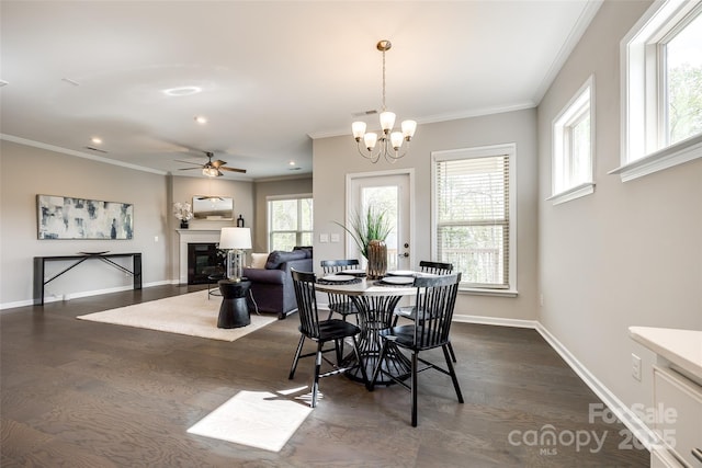 dining space with baseboards, a wealth of natural light, ornamental molding, and a glass covered fireplace