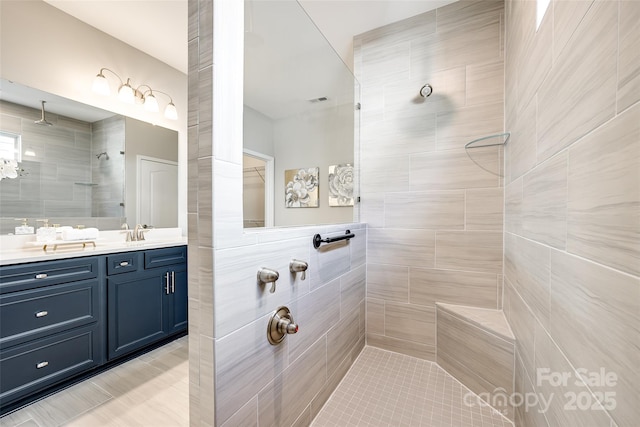 bathroom featuring visible vents, a walk in shower, and vanity