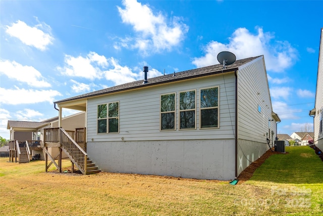 rear view of house with central AC, a deck, stairway, and a yard