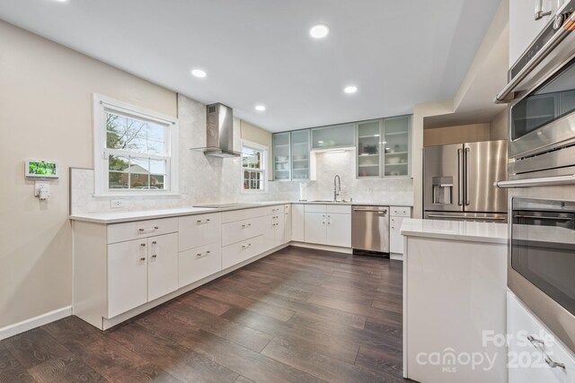 8308 Knights Bridge Rd, Charlotte, NC 28210 - kitchen featuring tasteful backsplash, glass insert cabinets, stainless steel appliances, dark wood finished floors, and wall chimney exhaust hood