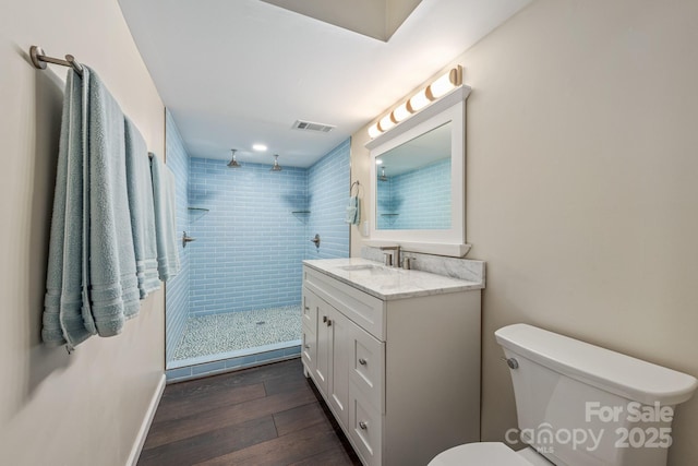 8308 Knights Bridge Rd, Charlotte, NC 28210 - bathroom featuring a tile shower, wood finished floors, visible vents, toilet, and vanity