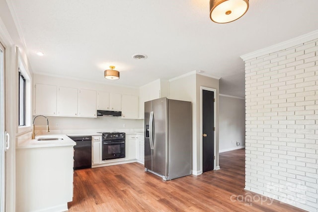 kitchen featuring light countertops, visible vents, under cabinet range hood, a sink, and black appliances