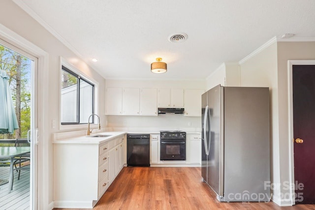 kitchen featuring light countertops, visible vents, stainless steel fridge, black dishwasher, and a sink