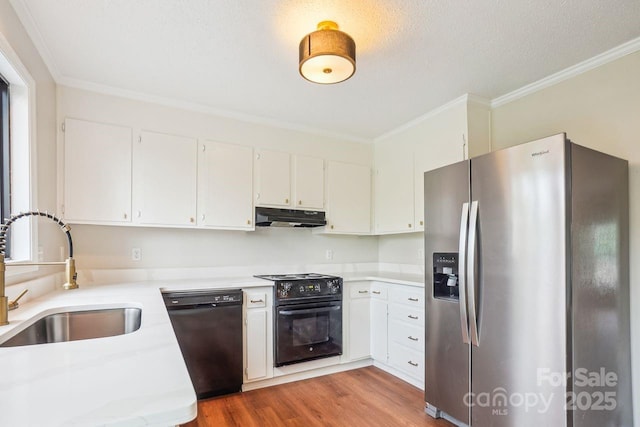 kitchen with light countertops, crown molding, under cabinet range hood, a sink, and black appliances