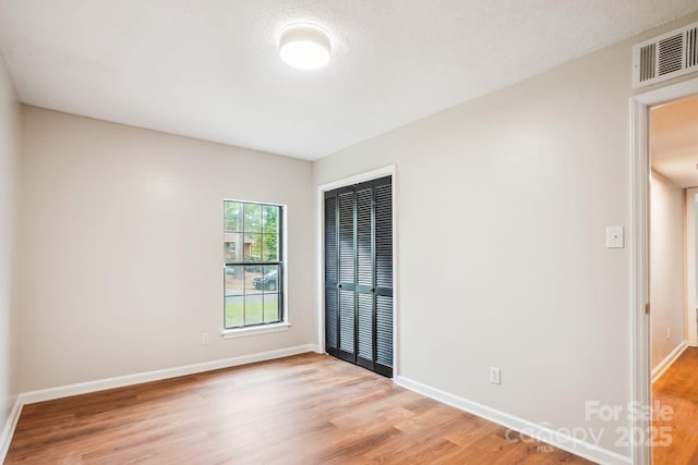 empty room featuring baseboards, visible vents, and light wood-type flooring