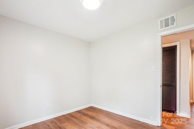 empty room featuring baseboards, visible vents, and wood finished floors