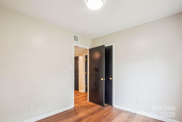 unfurnished room featuring visible vents, baseboards, and wood finished floors