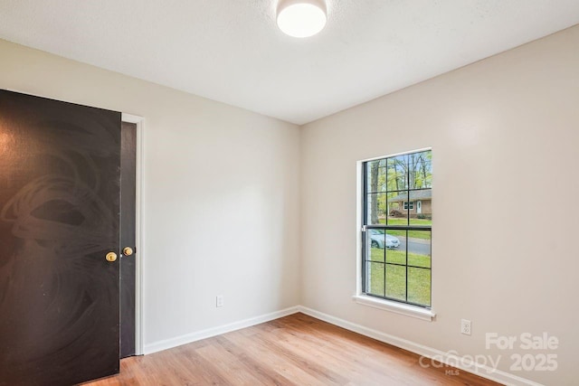 unfurnished room featuring light wood finished floors, baseboards, and a healthy amount of sunlight
