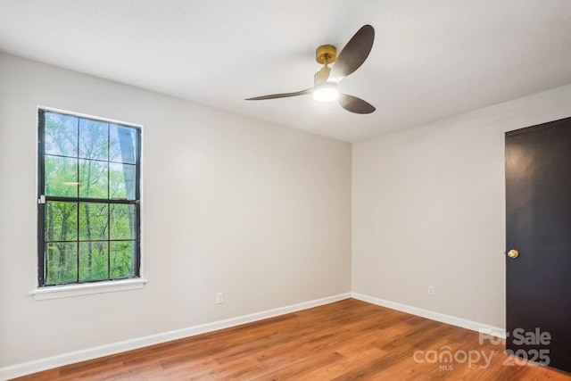 spare room with baseboards, wood finished floors, and a ceiling fan