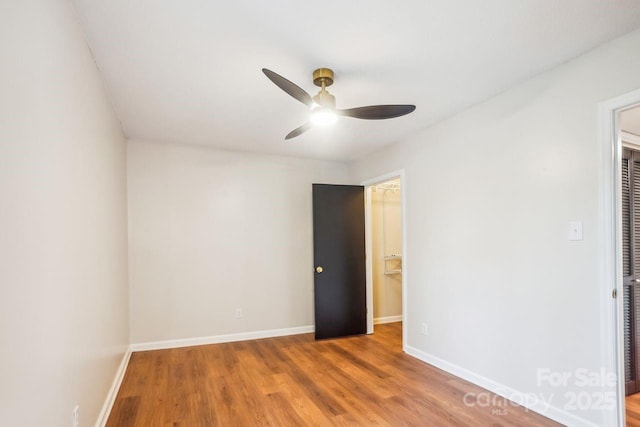 unfurnished bedroom with a walk in closet, baseboards, ceiling fan, a closet, and wood finished floors