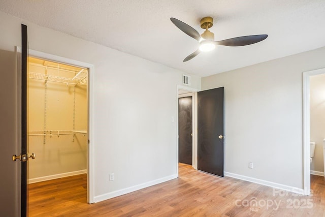 unfurnished bedroom with a closet, wood finished floors, and a walk in closet