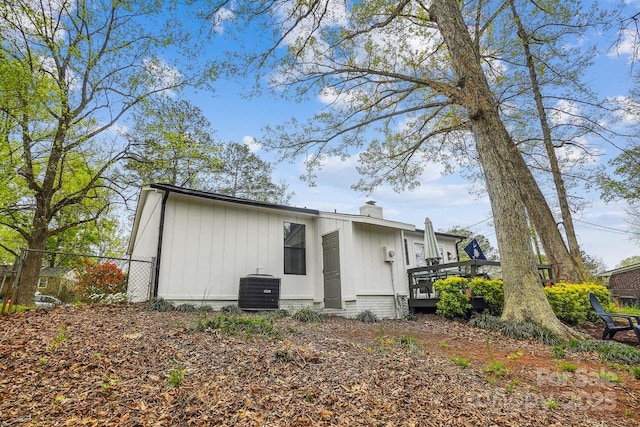 rear view of house featuring a chimney, fence, central AC, and a wooden deck