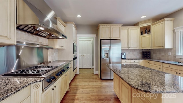 6108 Mcilwaine Rd, Huntersville, NC 28078 - kitchen with dark stone counters, wall chimney range hood, light wood-type flooring, backsplash, and appliances with stainless steel finishes