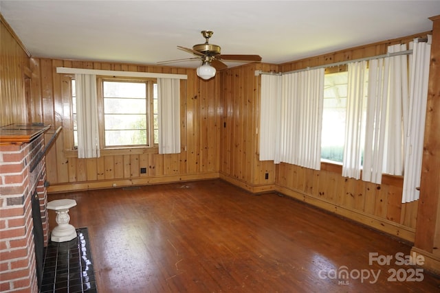 unfurnished room with wood walls, wood finished floors, ceiling fan, and baseboards