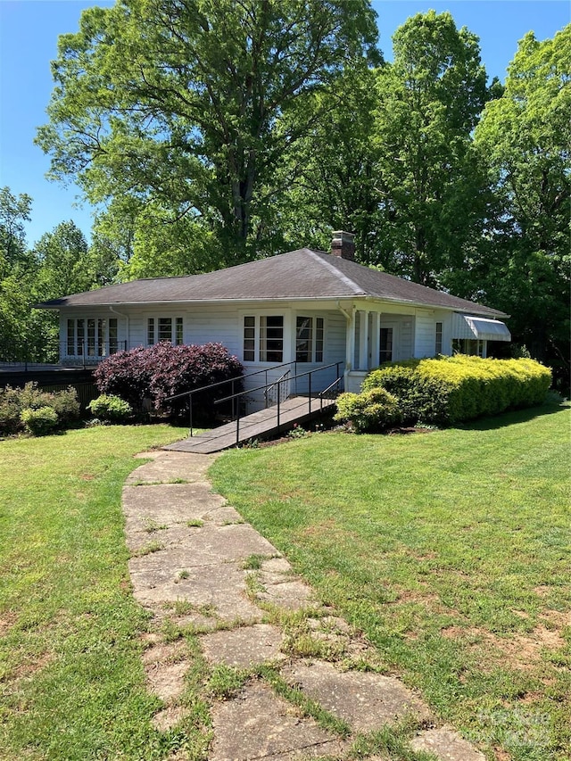 view of front of home with a chimney and a front yard