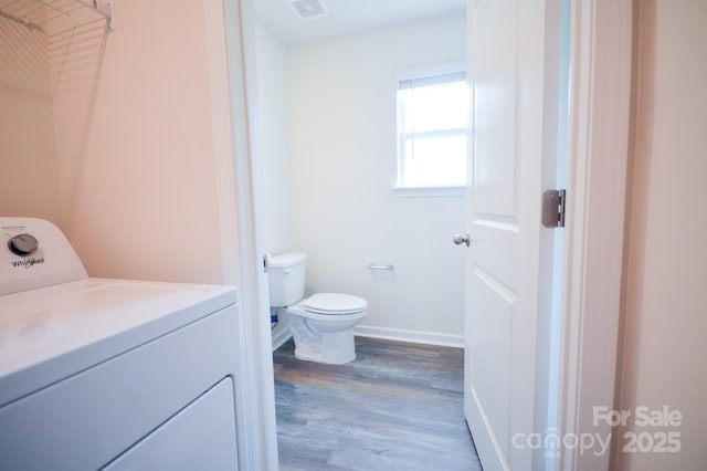 bathroom featuring wood finished floors, baseboards, toilet, washer / clothes dryer, and visible vents
