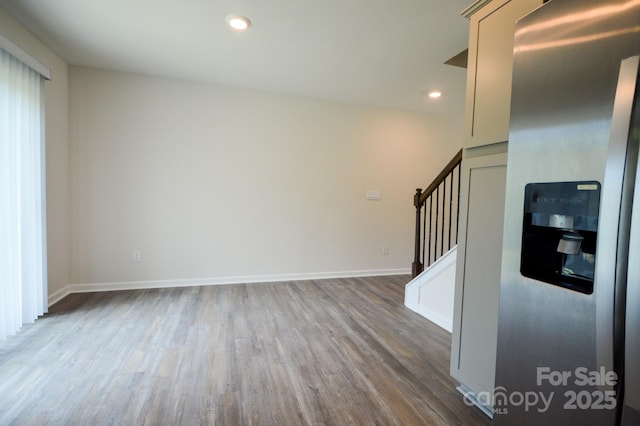 unfurnished living room with baseboards, wood finished floors, recessed lighting, and stairs