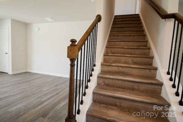 staircase with baseboards and wood finished floors