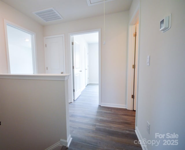 hallway with attic access, baseboards, visible vents, and dark wood finished floors