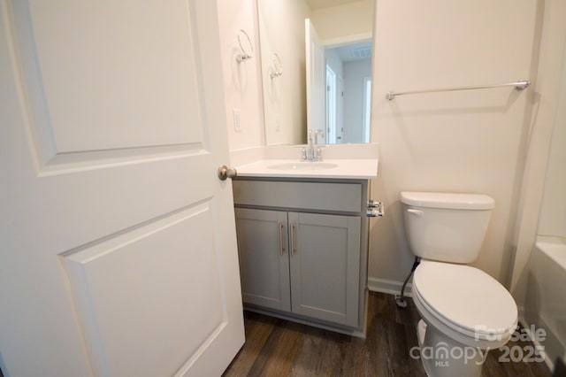 bathroom with wood finished floors, a bathtub, vanity, and toilet