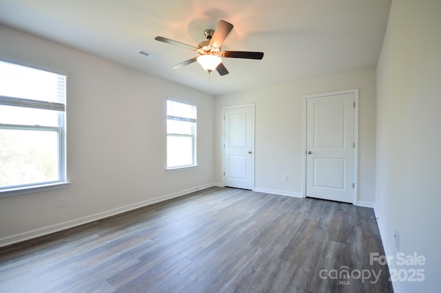 unfurnished bedroom with a ceiling fan, baseboards, dark wood-style flooring, and visible vents