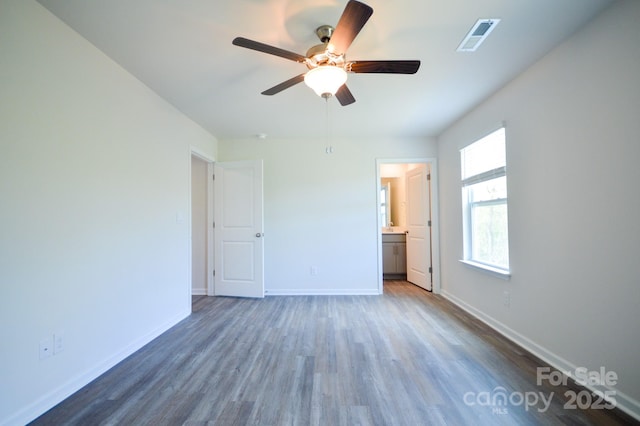 unfurnished bedroom with ensuite bathroom, baseboards, visible vents, a ceiling fan, and wood finished floors