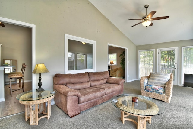 living area with carpet floors, baseboards, high vaulted ceiling, and ceiling fan