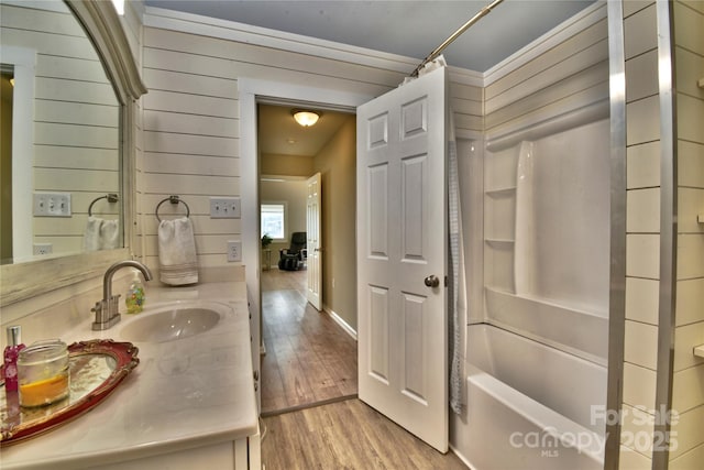 full bath with shower / tub combo, baseboards, vanity, and wood finished floors