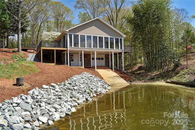 rear view of property with an attached garage, a sunroom, and a deck