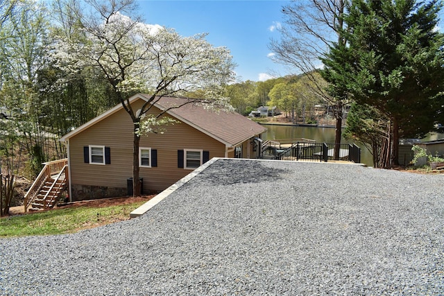 view of side of property featuring stairway, a water view, and cooling unit