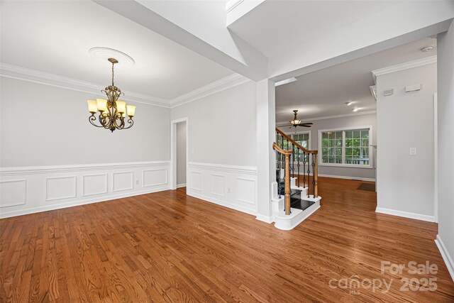 206 Coburn Ct, Fort Mill, SC 29715 - unfurnished room with a chandelier, crown molding, stairway, wood finished floors, and a wainscoted wall