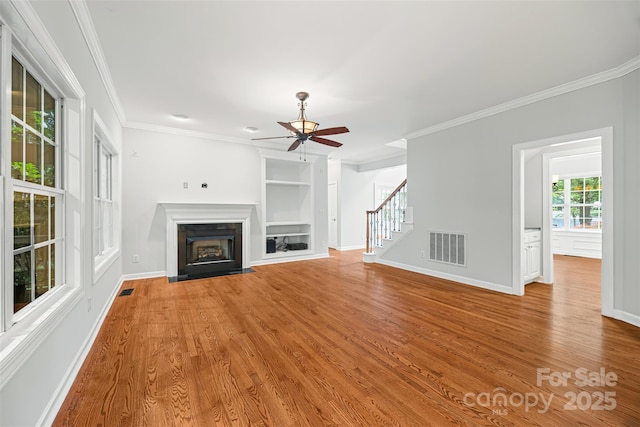 206 Coburn Ct, Fort Mill, SC 29715 - unfurnished living room with stairs, a ceiling fan, crown molding, wood finished floors, and built in shelves