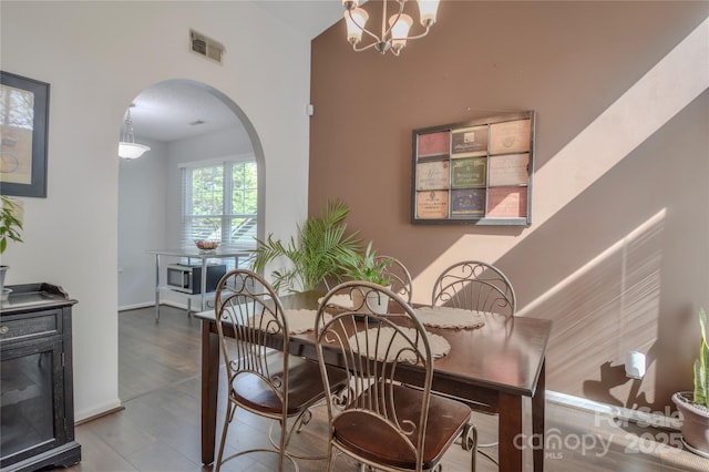 dining space featuring arched walkways, baseboards, visible vents, and a notable chandelier