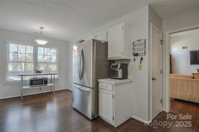 kitchen featuring a textured ceiling, white cabinets, light countertops, appliances with stainless steel finishes, and dark wood-type flooring