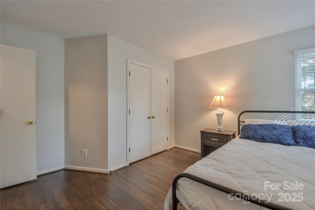 bedroom featuring baseboards, a textured ceiling, and wood finished floors