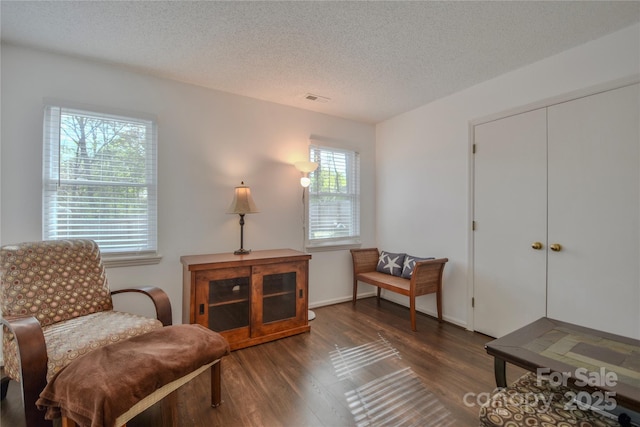 sitting room featuring visible vents, a textured ceiling, and wood finished floors