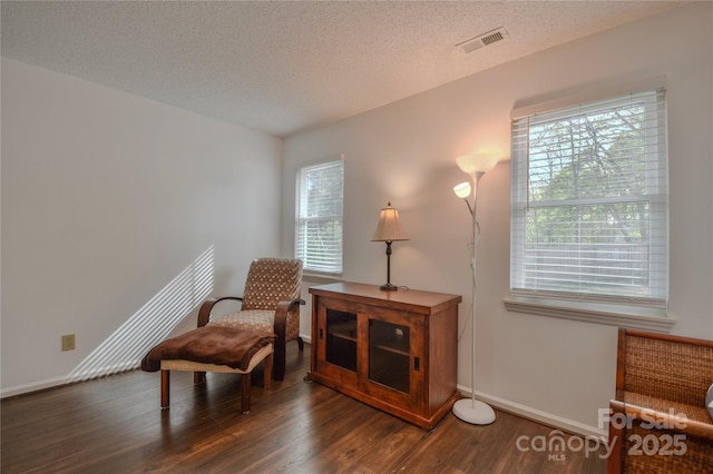 sitting room with a textured ceiling, a wealth of natural light, visible vents, and wood finished floors