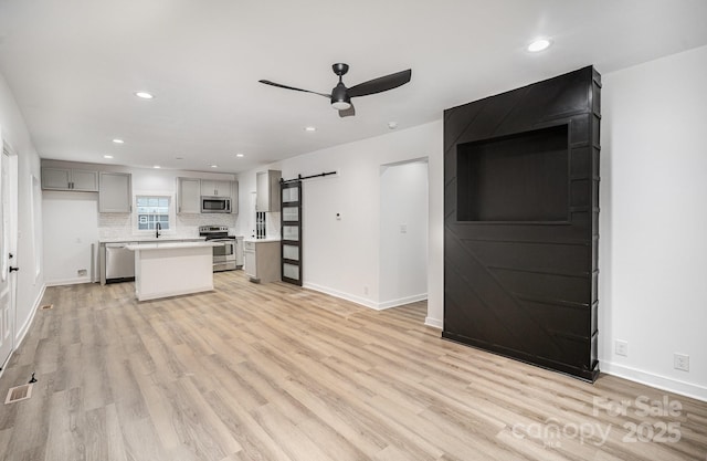 308 Birch St, Lowell, NC 28098 - kitchen featuring stainless steel appliances, a barn door, a ceiling fan, light wood-style floors, and recessed lighting