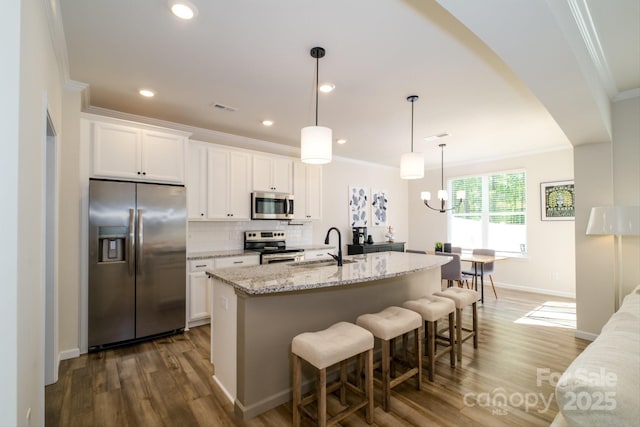 kitchen featuring an island with sink, crown molding, appliances with stainless steel finishes, a sink, and wood finished floors