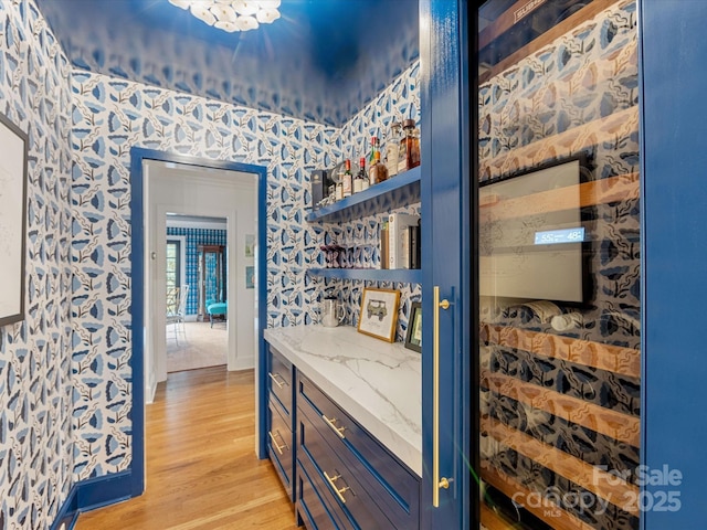 interior space featuring light wood finished floors, baseboards, and wallpapered walls