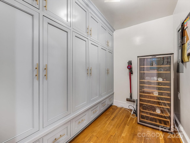 mudroom with baseboards, wine cooler, and light wood-style floors