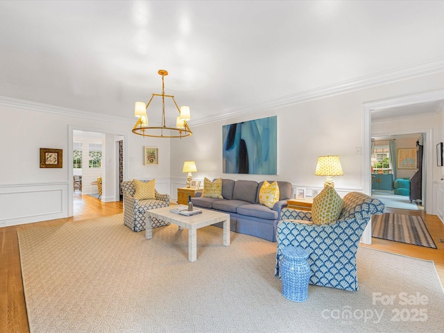 living room featuring a wainscoted wall, ornamental molding, and a notable chandelier