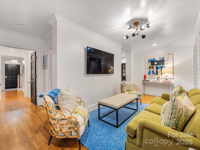 living area featuring an inviting chandelier, crown molding, baseboards, and light wood finished floors