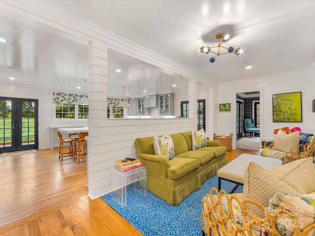 living area featuring recessed lighting, french doors, wood-type flooring, ornamental molding, and a notable chandelier