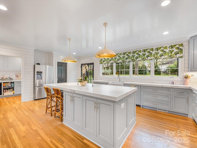 kitchen with a kitchen island, gray cabinets, stainless steel fridge, and light wood-type flooring
