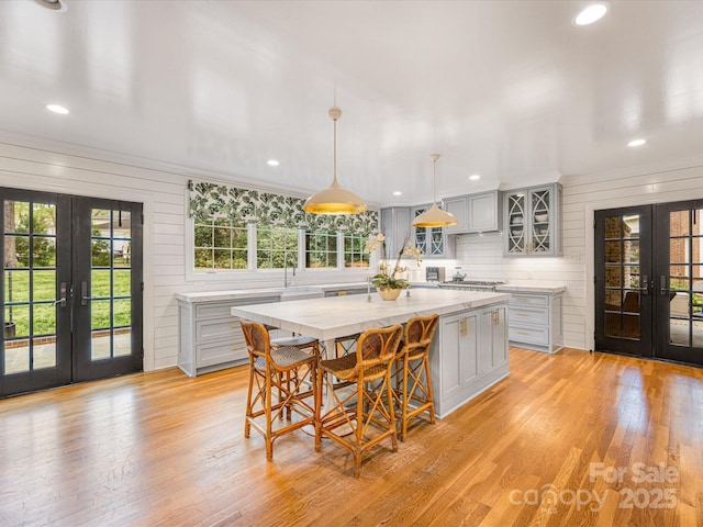 kitchen with french doors, hanging light fixtures, gray cabinetry, and light wood finished floors