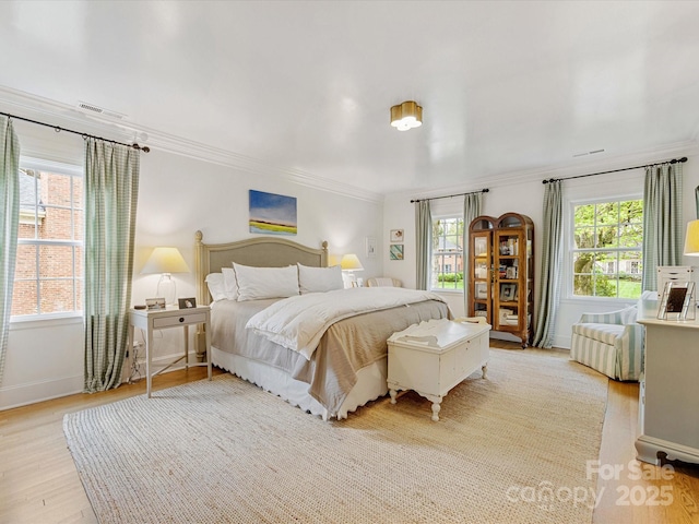 bedroom featuring light wood-style flooring, crown molding, baseboards, and visible vents